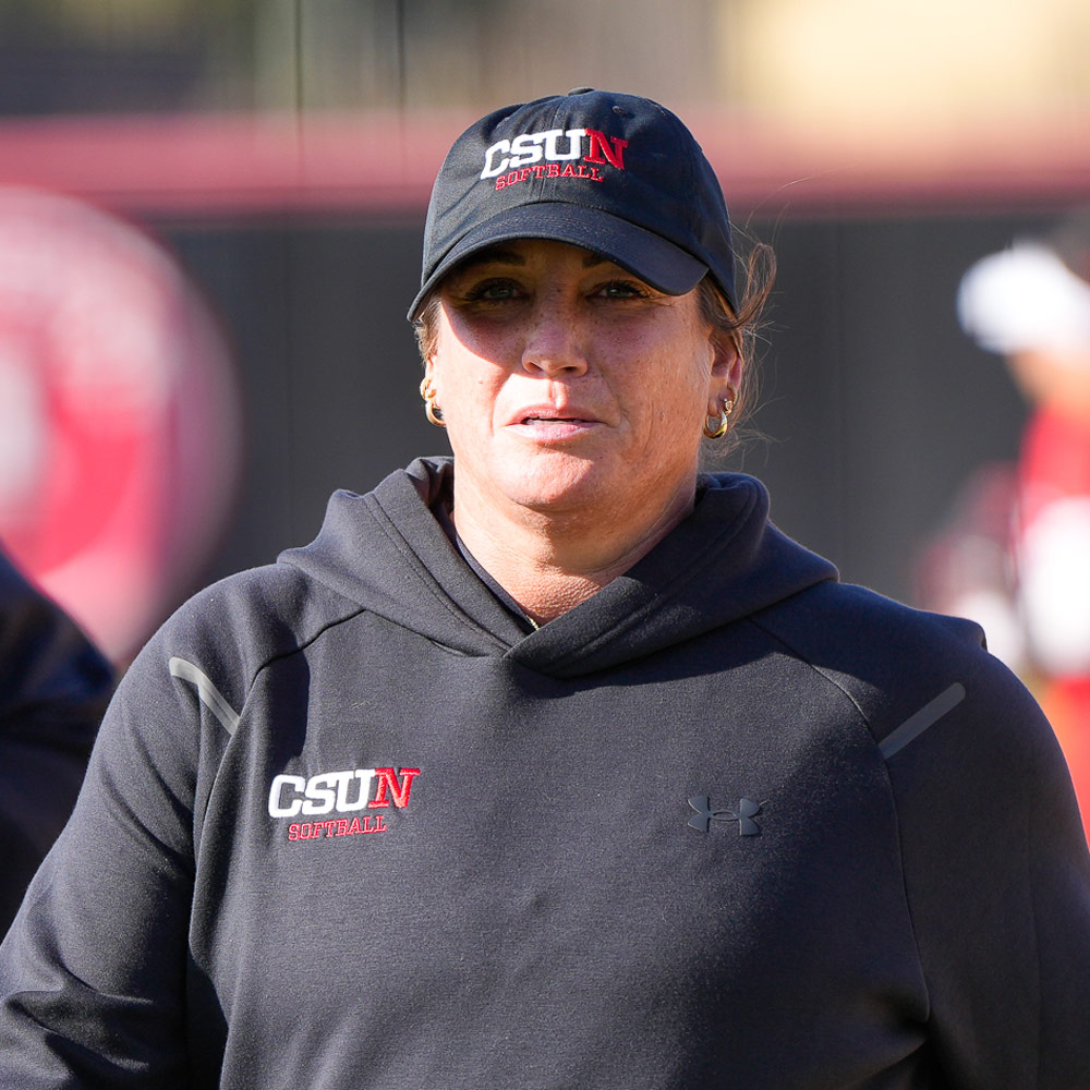 Headshot of a woman wearing a black CSUN Softball baseball cap and a black CSUN Softball hooded sweatshirt.