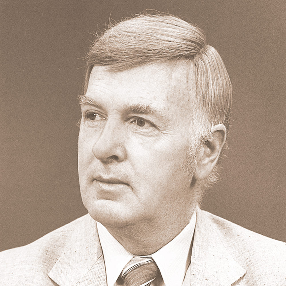 Black and white portrait of a white man in a light suit and tie, looking away from the camera.