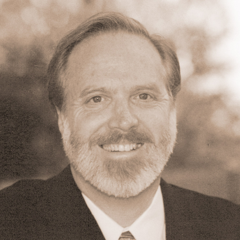 Portrait of a middle-aged white man with a beard, smiling in a suit and tie.