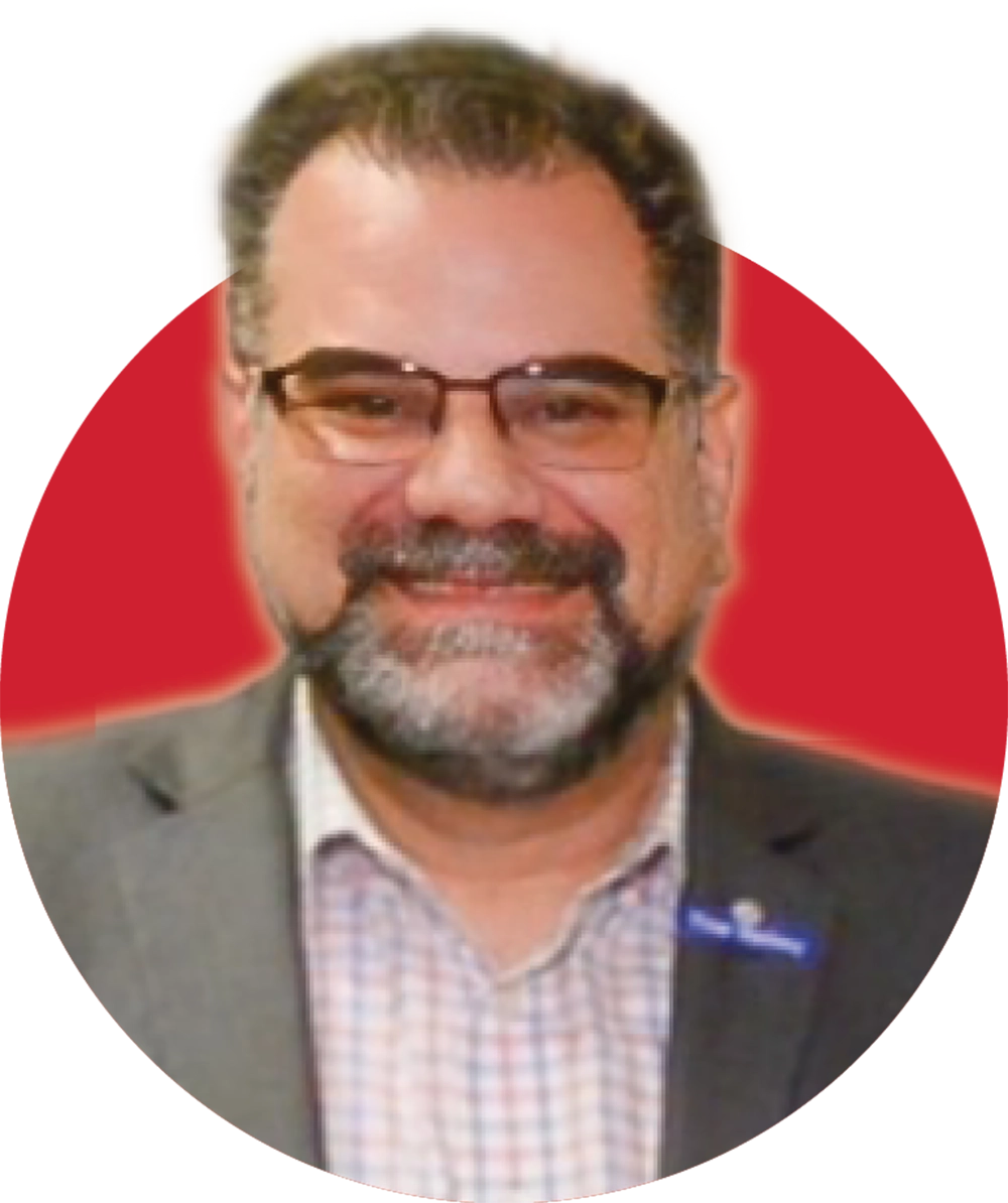 Headshot of a smiling man with glasses and a beard, wearing a suit jacket and collared shirt, against a red and white background.