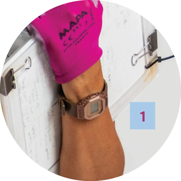 A close-up of a person’s wrist wearing a metallic digital watch and a bright pink MAPA brand glove, holding a waterproof clipboard with handwritten notes secured by binder clips.