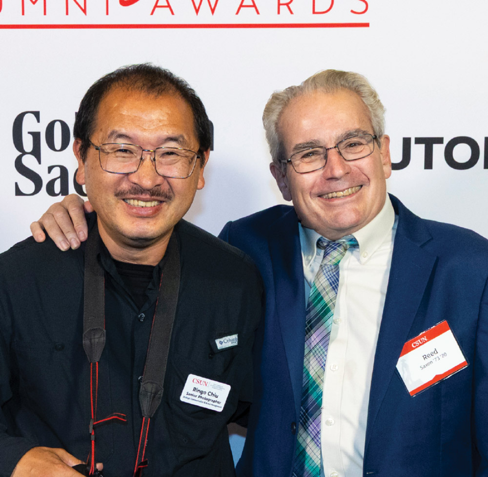 A photographer and a CSUN alumnus smiling with arms around each other at an awards event.