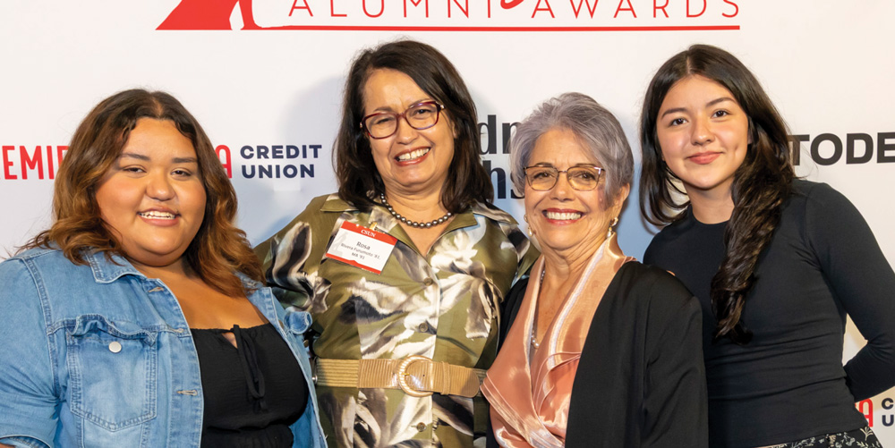 Four women smiling and posing together against a CSUN Alumni Awards backdrop.