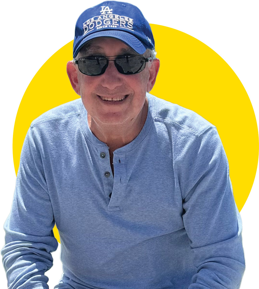 An older man wearing a blue Los Angeles Dodgers baseball cap and sunglasses, set against a yellow circle.
