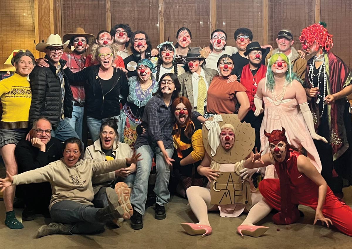 A large, diverse group of people dressed in creative costumes posing together, nearly all wearing red clown noses.