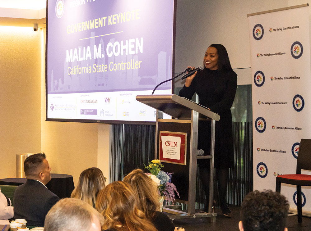 California State Controller Malia M. Cohen speaks at a podium during a keynote address in front of an audience.
