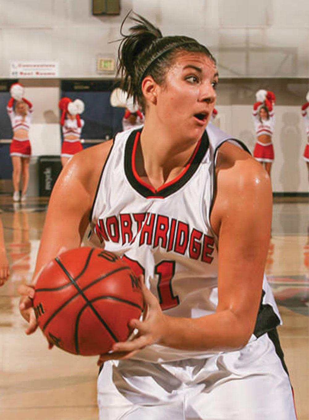 Katie Holloway Bridge in a white Northridge jersey holding a basketball during a game.