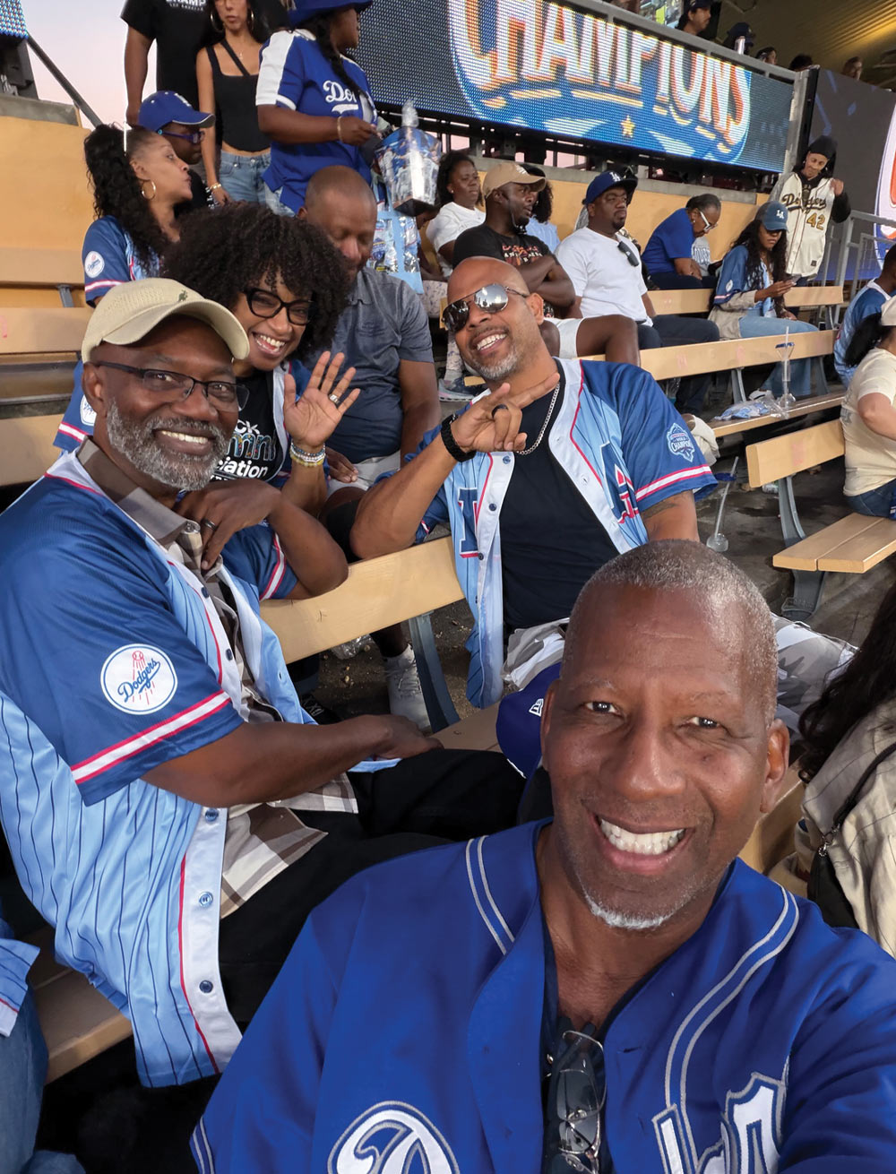 Joaquin Macias, Gigi McGuire, Charles Humphrey, and others wearing blue jerseys taking a selfie together in the stadium stands.