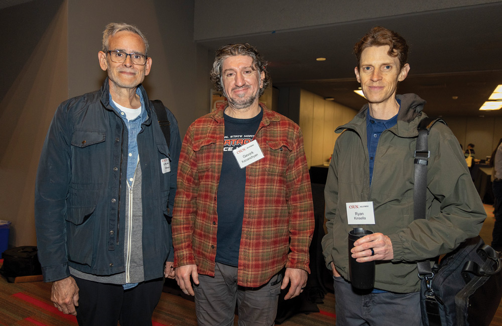 Gevork Kazanchyan, Ryan Kinsella, and another person wearing jackets and name tags standing together indoors at an event.